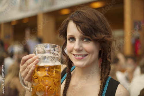  German woman wearing traditional dirndl and holding a beer mug at Oktoberfest