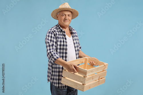 Elderly farmer holding a wooden empty crate photo