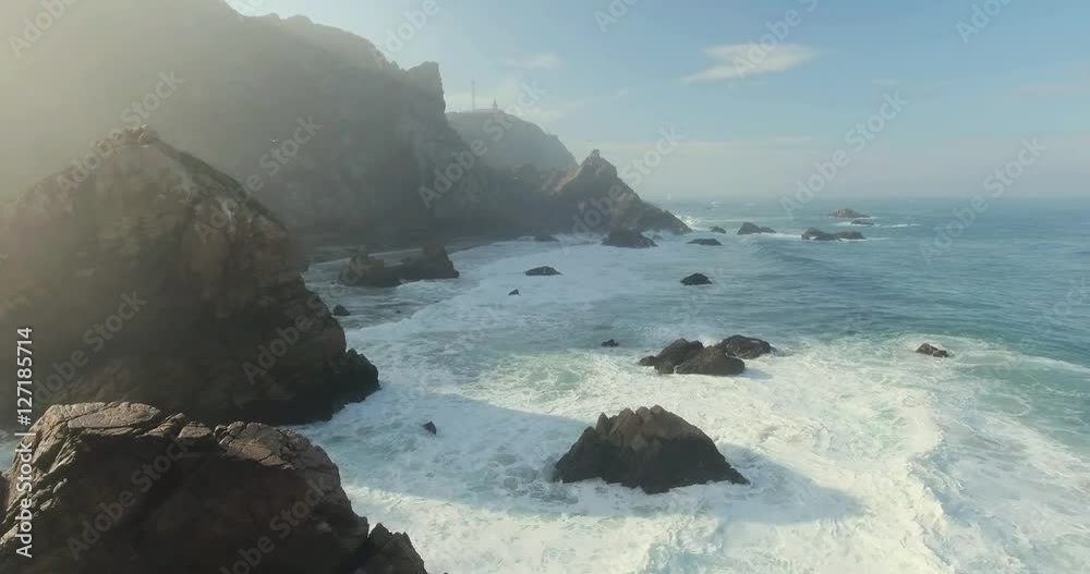 Beautiful aerial or drone shot along the coast of Portugal on a sunny day. Epic cliffs and ocean waves birds eye view during sunrise. Untouched, powerful nature. Cabo da Roca, Portugal Europe.