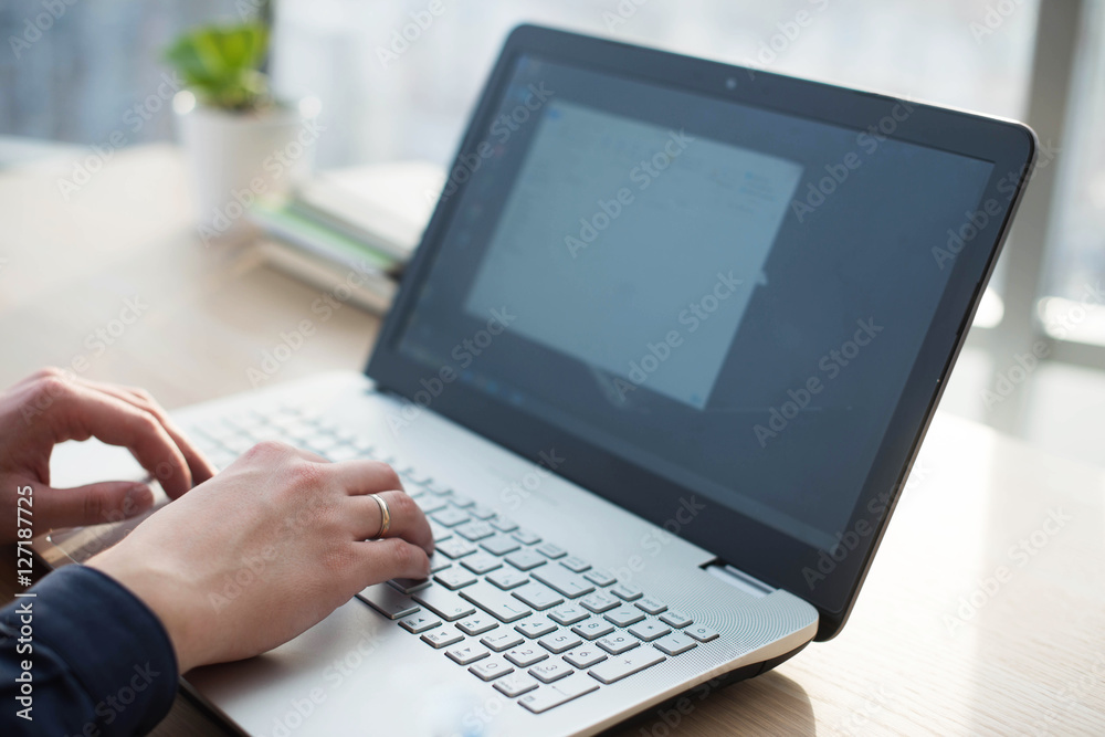 Hands typing on a laptop keyboard. A man works in an office at his workplace Hands typing on a laptop keyboard. A man works in an office at his workplace