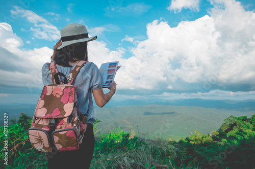 Woman traveler seeing on map with mountain view and cloudy sky in vintage tone