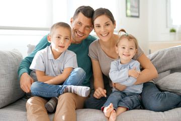 Happy family of four sitting on sofa