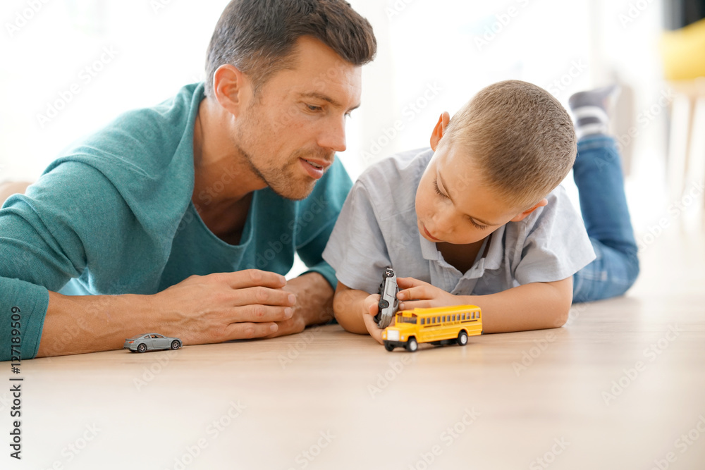 Daddy with son playing with car toys, laying on floor Daddy with son playing with car toys, laying on floor