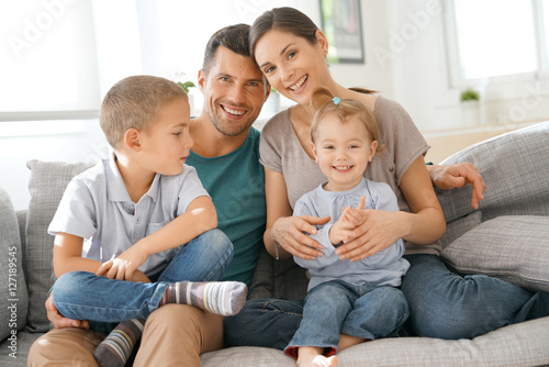 Happy family of four sitting on sofa