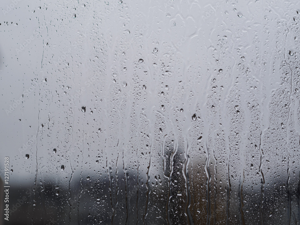 Regentropfen auf Fensterscheibe mit Gebäuden im Hintergrund Regentropfen auf Fensterscheibe mit Gebäuden im Hintergrund