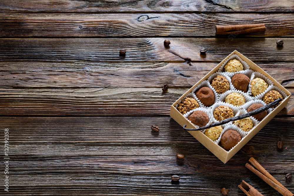 Box of chocolates, various chocolate truffles, white chocolate and praline on wooden table. Top view. Copy space for text. Sweet gift concept Box of chocolates, various chocolate truffles, white chocolate and praline on wooden table. Top view. Copy space for text. Sweet gift concept