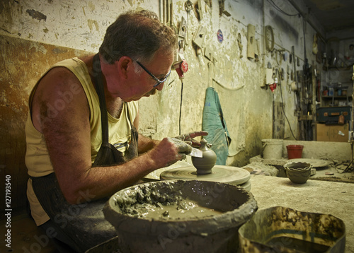 Potter in workshop working on earthenware vessel