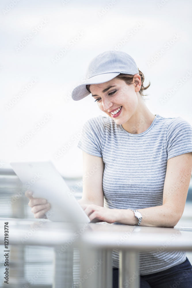 Smiling woman with baseball cap looking at tablet Smiling woman with baseball cap looking at tablet