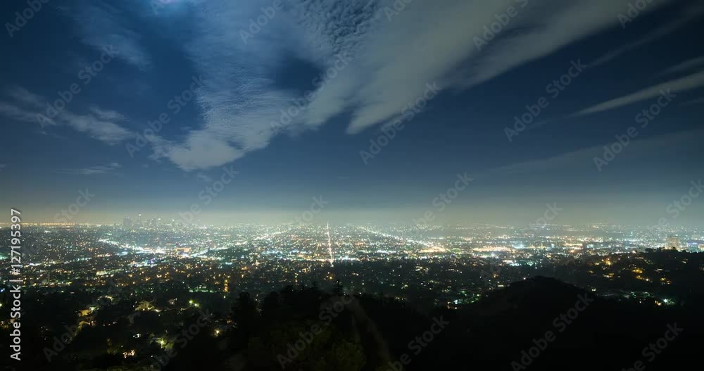 Los Angeles, California, USA - view from Griffith Observatory at City of Los Angeles facing south at clear night with moonlight and a few moving clouds - Timelapse with pan right to left 