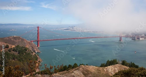 San Francisco, California, USA - Golden Gate Bridge and San Francisco Bay from famous Hawk Hill lookout at sunny day with blue sky - Timelapse with pan left to right