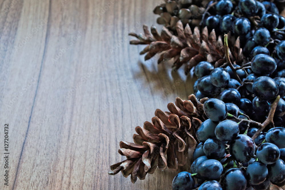 Grapes and pine cones on a wooden table