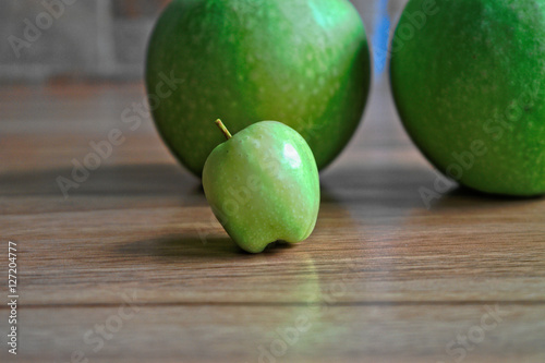 Tiny green apple on a wooden table