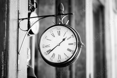 Black and white photo of a vintage clock on a wooden wall 