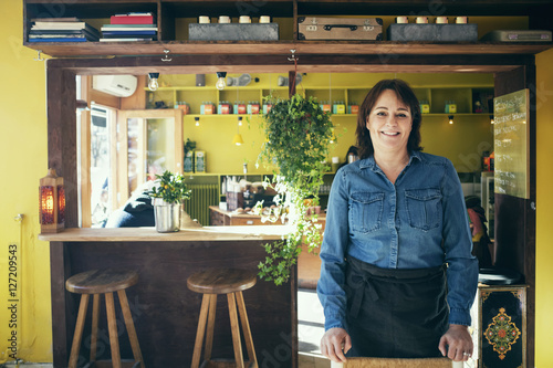 Portrait of happy owner standing in coffee shop photo