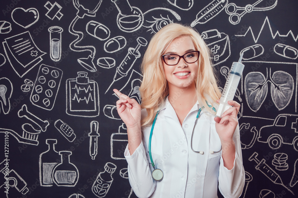 Beautiful blonde woman doctor in glasses and white coat holding syringe on dark background with pattern