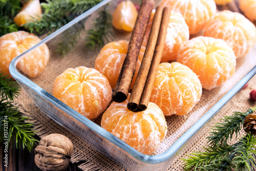 Peeled mandarines Glass dish Cinnamon sticks photo