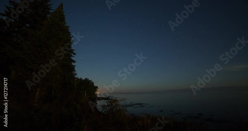 Tongue Point, Washington, USA - clear starry night with moonlight and moving shadows over the coast of Tongue Point with ferries at the ocean - Timelapse with zoom out photo