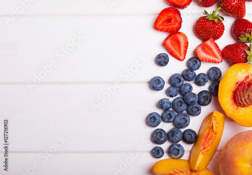 Blueberries, strawberries and peaches on the white table