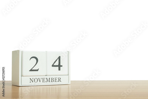Closeup surface white wooden calendar with black 24 november word on blurred brown wood desk isolated on white background with copy space , selective focus at the calendar