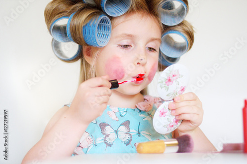 Adorable funny little girl making makeup with mother cosmetics