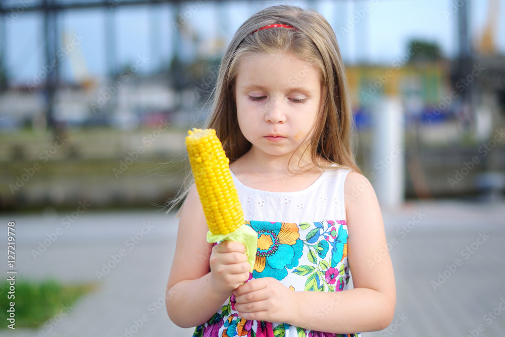 Adorable funny girl eating corn on the cob on sunny summer day Adorable funny girl eating corn on the cob on sunny summer day