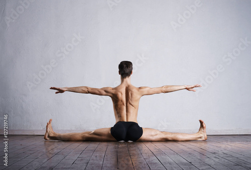 Handsome ballet dancer sitting on splits