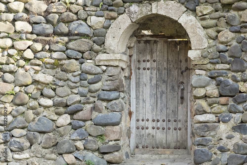 An old wooden door at the entrance to an ancient church in a sto