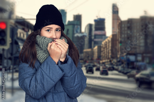 Konstfotografi Portrait of a pretty frozen woman in coat with scarf and hat standing  over  bac