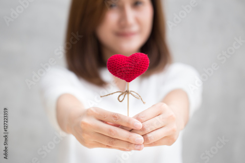 Giving love gift, Asian woman hand hold give beautiful red heart sweet loving symbol of take care or charity help to you. photo