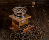 Coffee mill with grains on dark rustic background