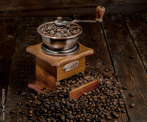 Coffee mill with grains on dark rustic background