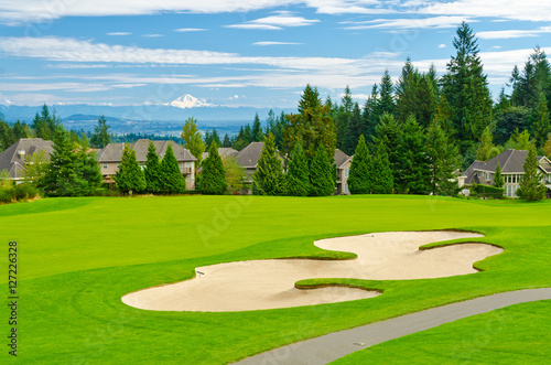 Beautiful golf place with gorgeous green and fantastic snow mountain view over blue sky with white clouds.