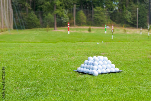 Piramid of golf balls on driving range. Shallow depth of field. Focus on the pyramid of golf balls.