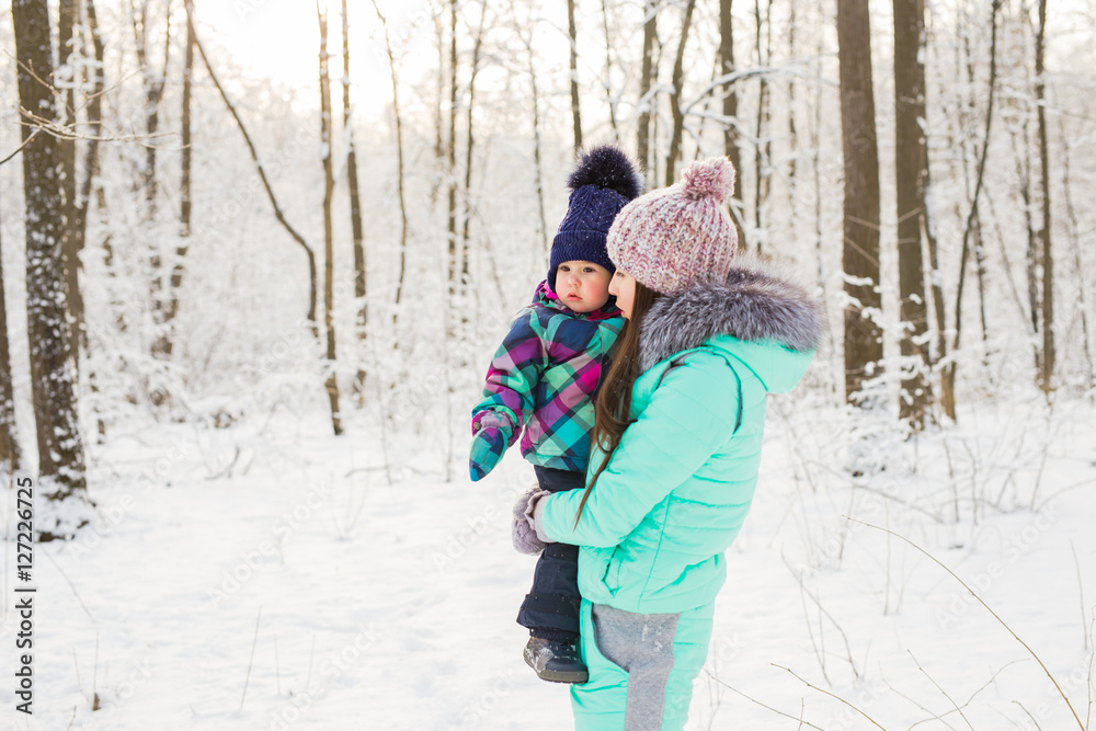 Young brunette mother with her daughter outdoors. Winter time