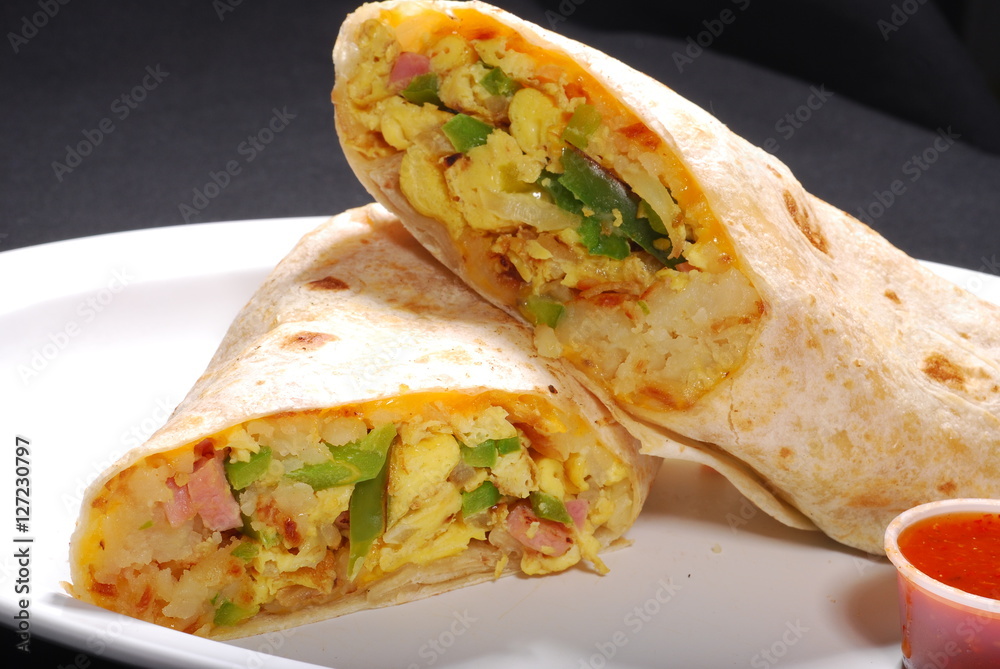 Breakfast Burrito with egg and potatoes inside and red sauce Stock