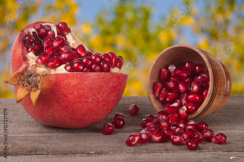 peeled pomegranate and garnet grains in a bowl on wooden background