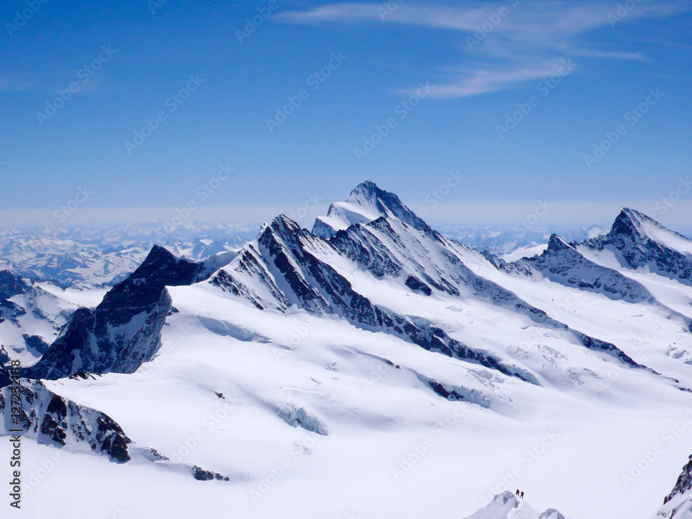 mountain guide and client descending a high alpine peak with a gigantic panorama of the Swiss Alps