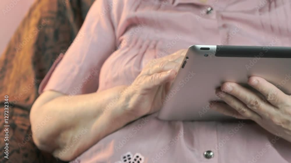 The old woman holding the silver tablet computer The old woman holding the silver tablet computer