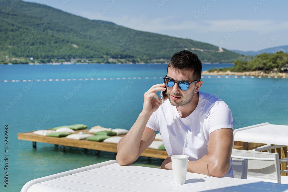 sad  young man talking on his smart phone at the beach.Summer holiday concept