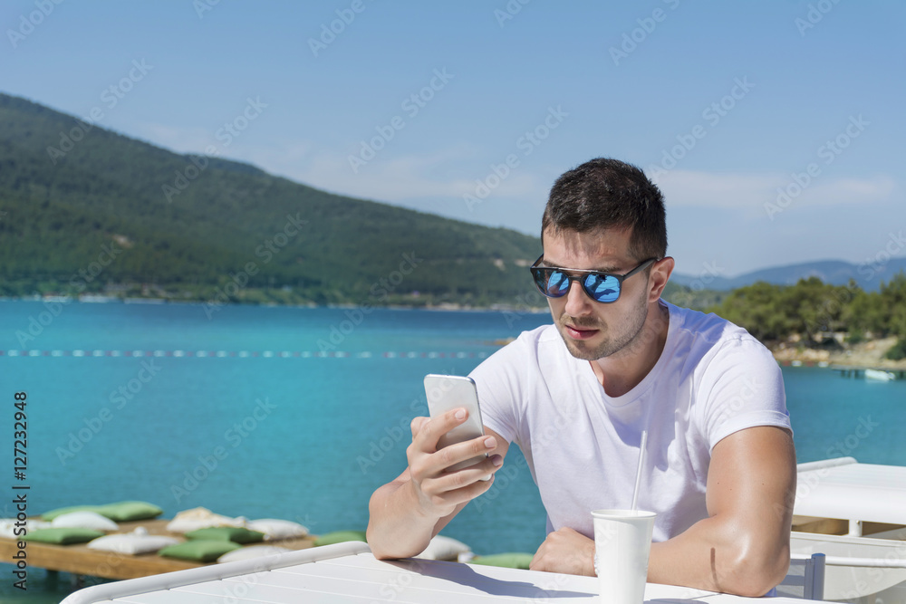 Portrait of young sad annoyed man , receiving bad sms on the beach