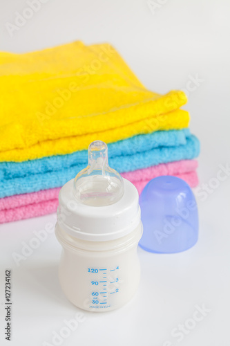 baby bottle with milk and towel on white background