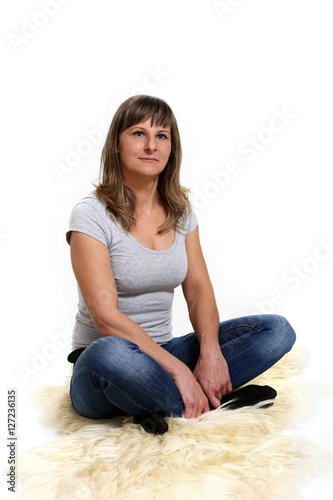 Kobieta siedzi na skórze naturalnej, na białym tle.