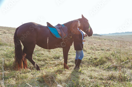 Adorable brunette young woman goes with her horse
