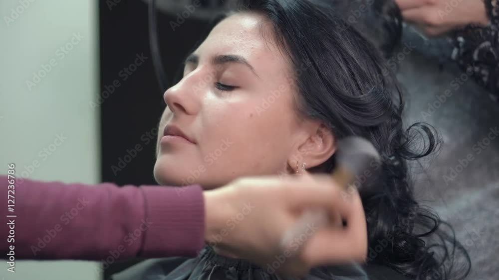 Makeup artist on applying blush on cheeks with powder brush Makeup artist on applying blush on cheeks with powder brush