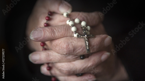 old hands praying and holding a rosary