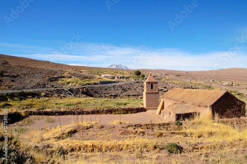 Long shot of the old church in Socaire made out of bricks and its surroundings with a blue sunny sky close to San Pedro de Atacama in Chile, South America