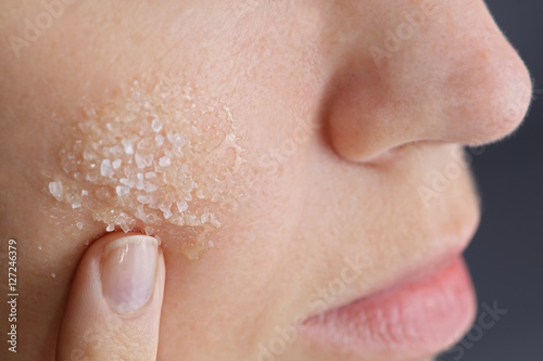 Woman applying homemade facial scrub from honey and sea salt. Skin care concept