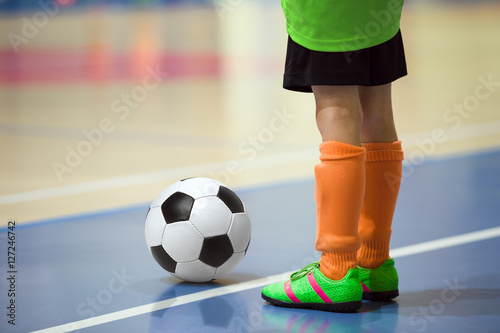 Football futsal training for children. Indoor soccer young player with a soccer ball in a sports hall. Sport background.