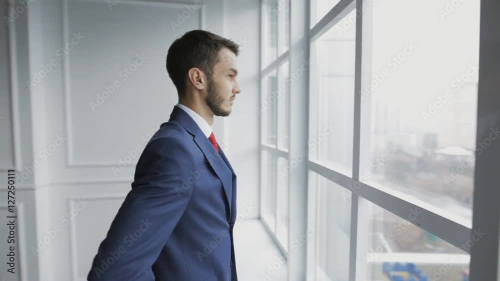 Businessman in white office thinking standing at window Businessman in white office thinking standing at window