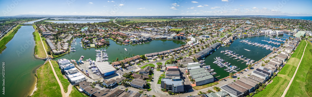 Aerial panorama of Patterson River and Patterson Lakes suburb on bright sunny day. Houses nested near water with moored boats nearby. Melbourne, Victoria, Australia